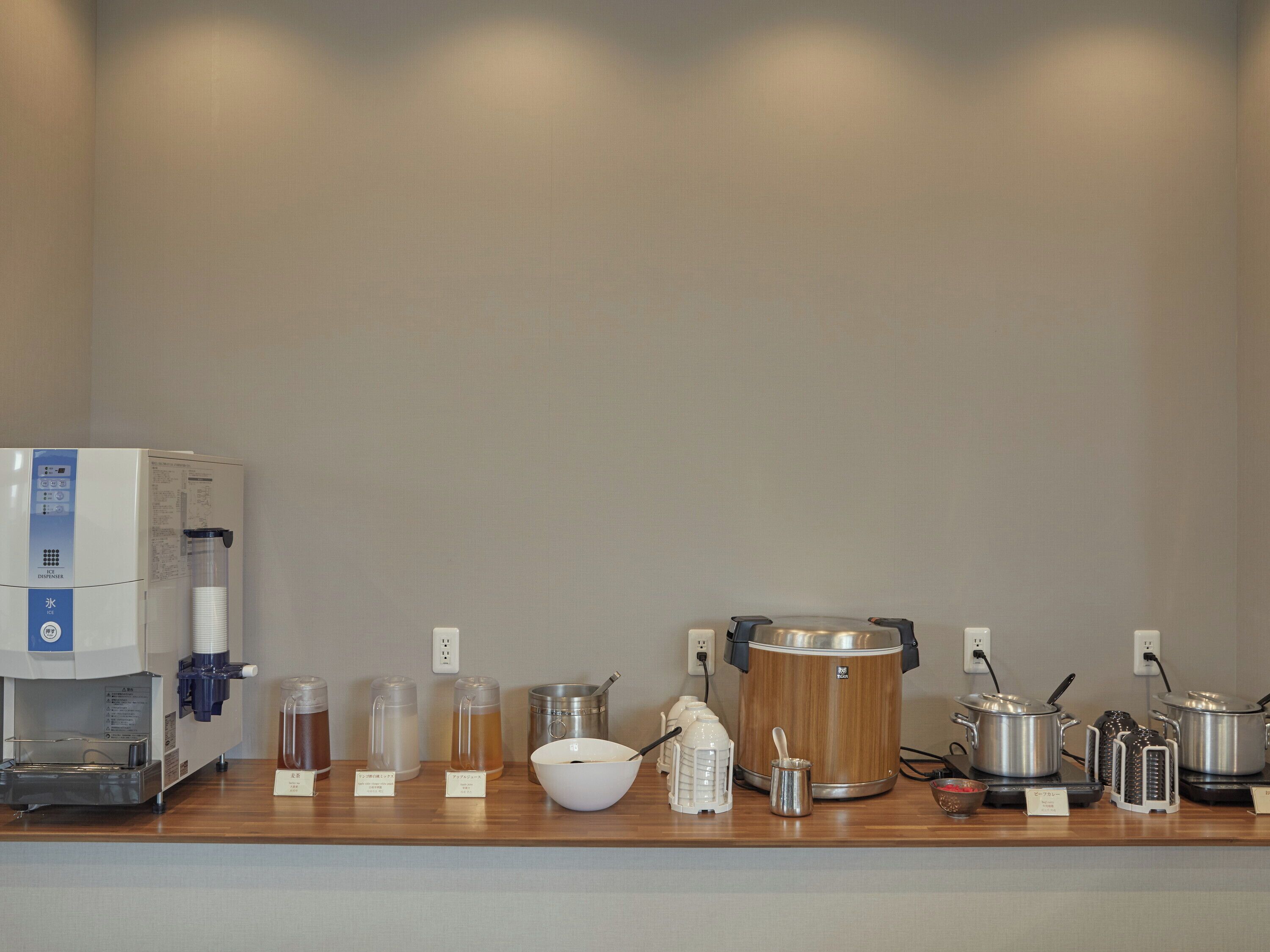 Una zona de cocina con cafetera, dispensadores de té y ollas.