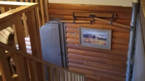 A rustic cabin interior with a wooden staircase, a mounted deer head, a framed landscape painting, and a small rug on the floor. - Our Guest house is a cozy get away, in a small town.  (Grey Eagle)