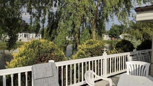En terrasse med hvide gelændere, et bord og to stole.