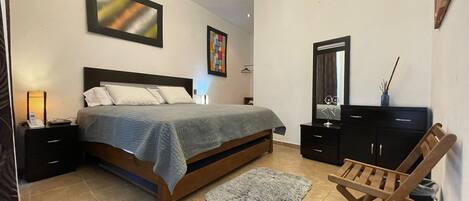 A bedroom with a bed, nightstands, a dresser, a mirror, and a chair.