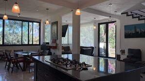 A modern kitchen with a central island, pendant lighting, and large windows offering views of greenery. - Casa Valle de Bravo la Peña  (Valle de Bravo)