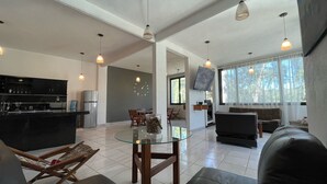 A spacious living area with a glass dining table, a sofa, and a TV mounted on the wall. - Casa Valle de Bravo la Peña  (Valle de Bravo)