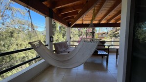 A hammock on a balcony with a view of trees and a building in the background. - Casa Valle de Bravo la Peña  (Valle de Bravo)