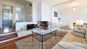 A living room with a glass coffee table, a beige sofa, and a fireplace.