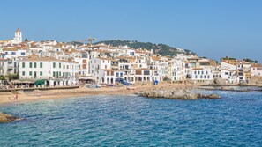 A coastal town with white buildings, a beach, and rocky shoreline.