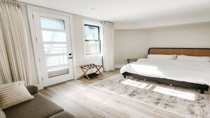Een slaapkamer met een groot bed, een bank, een klein tafeltje en een raam met gordijnen.
