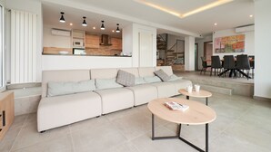 A modern living room with a sofa, coffee table, and dining area. - 2FIR02 Villa with private swimming pool (Lloret de Mar)