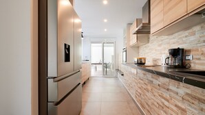 A modern kitchen with a wooden backsplash, stainless steel appliances, and a coffee maker on the counter. - 2FIR02 Villa with private swimming pool (Lloret de Mar)