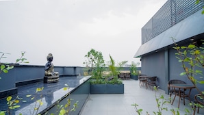A rooftop terrace with a Buddha statue, seating area, and potted plants. - Saltstayz Select - Golf Course Road & Sector 57 (Gurugram)