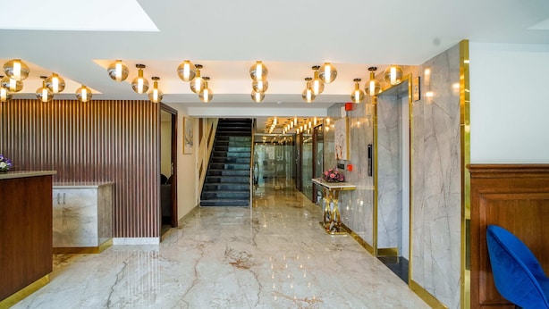 A hotel lobby with a marble floor, a reception desk, a staircase, and modern lighting fixtures. - Saltstayz Select - Golf Course Road & Sector 57 (Gurugram)