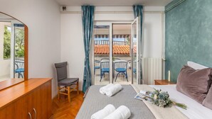 A hotel room with a bed, a desk, a chair, a balcony with a railing, and a view of the outside. - Family Resort Santa Maria I Apartment 1, Stara Novalja, Croatia (Stara Novalja)