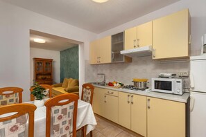 Une cuisine compacte avec des meubles de couleur jaune, un four à micro-ondes, une cuisinière et un coin repas comprenant une table et des chaises.