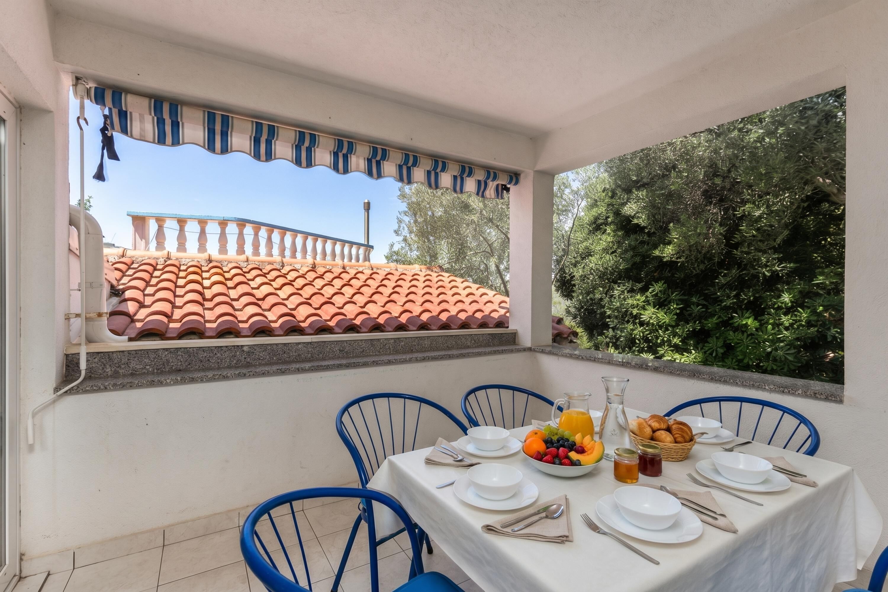 A dining area with a table set for six, a fruit bowl, and a basket of bread.