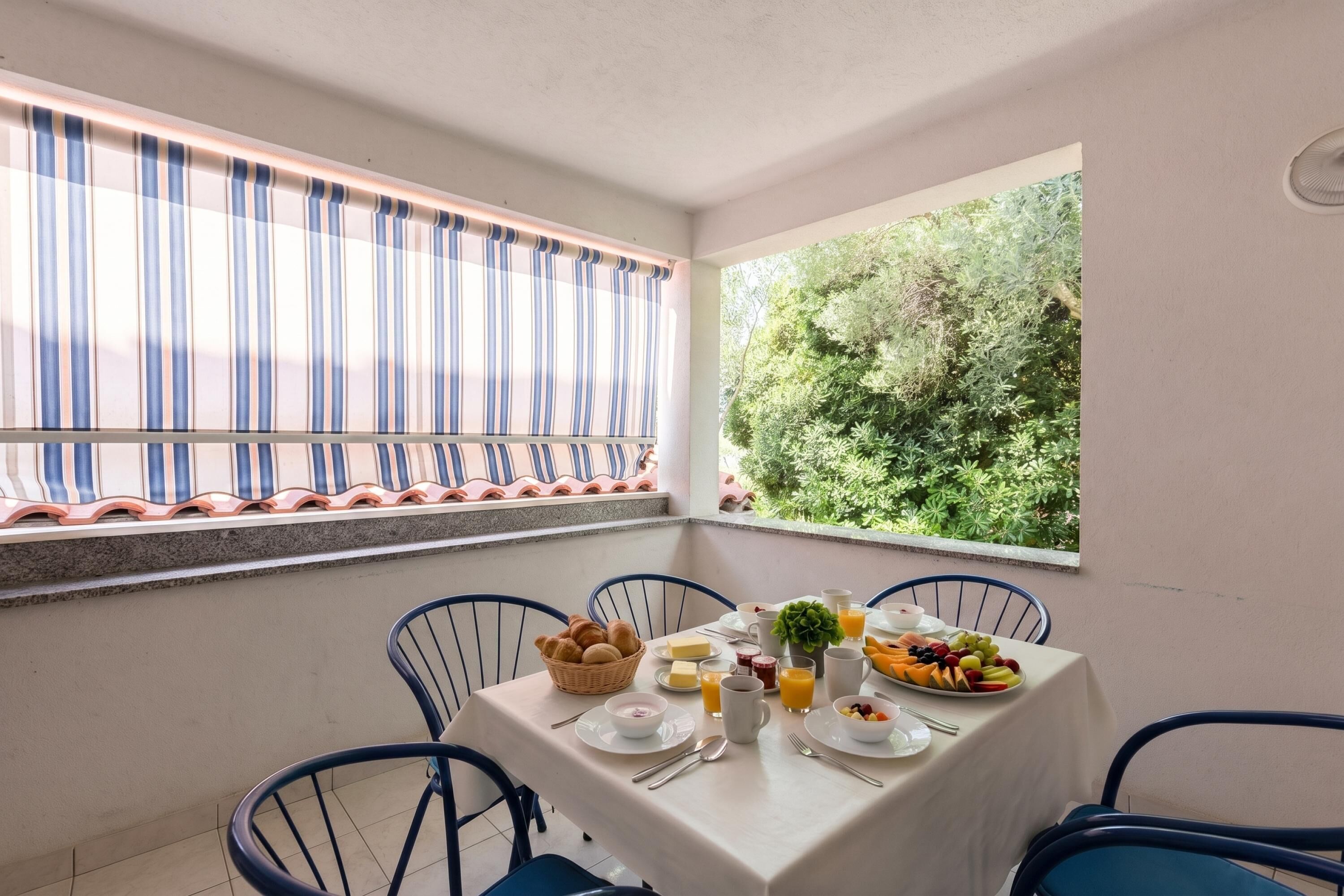 Uma sala de jantar com uma mesa posta para o café da manhã, incluindo frutas, pão e bebidas.
