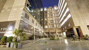 Un hôtel à plusieurs étages, doté d’un design moderne, avec une cour intérieure agrémentée de plantes en pot et d’un sol réfléchissant.