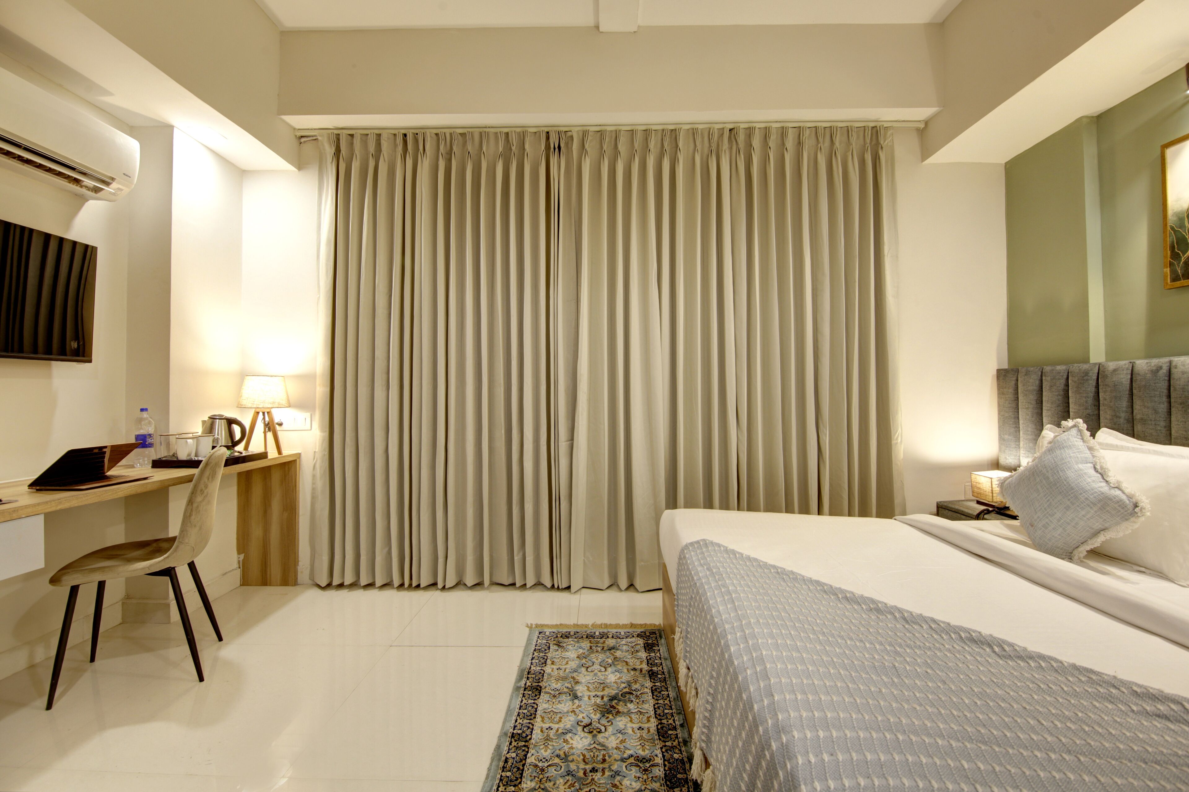 Ein Hotelzimmer mit Bett, Schreibtisch, Stuhl und Vorhängen.
