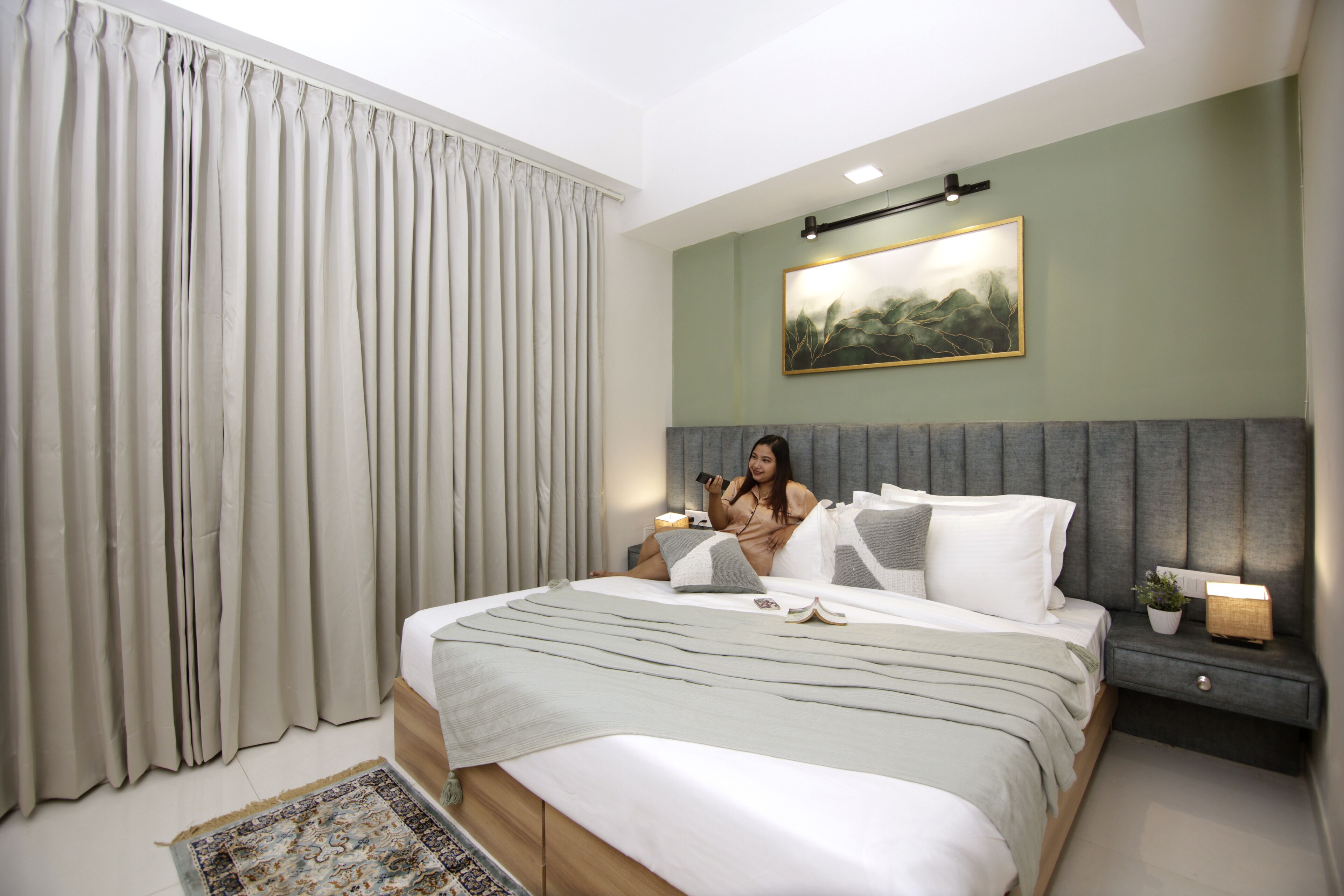 Een moderne slaapkamer met een groot bed, een nachtkastje, een bedlampje en een schilderij aan de muur.
