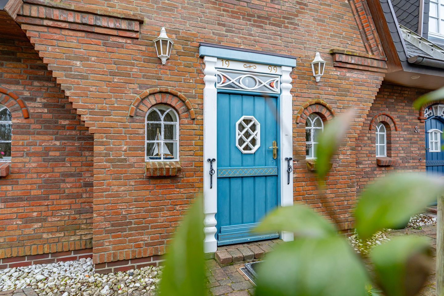 A brick building with a blue door, arched windows, and a small balcony.