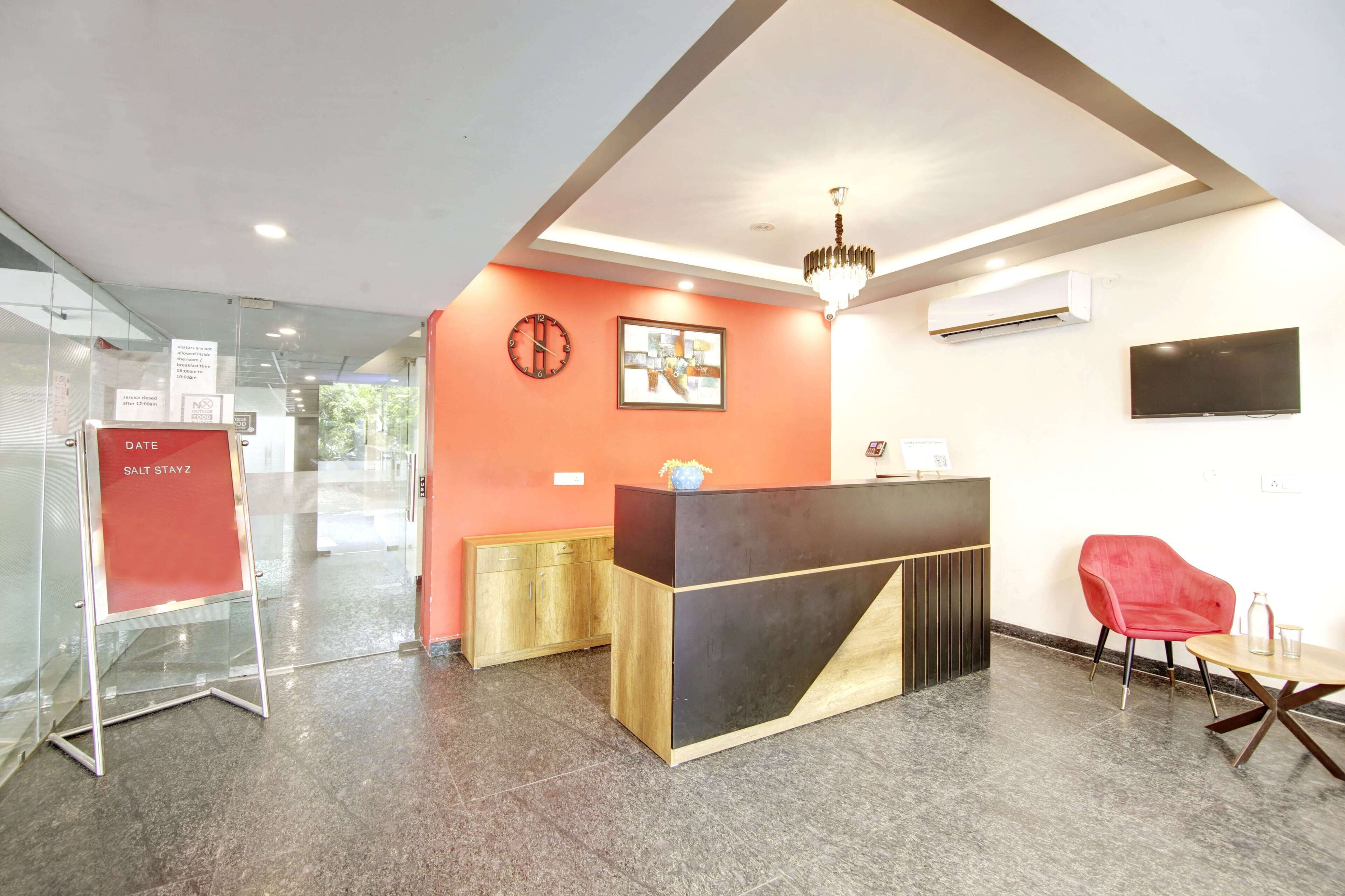 A reception area with a modern reception desk, a red chair, and a chandelier.