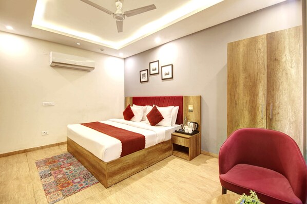 Une chambre à coucher avec un lit, une table de chevet, une chaise rouge, une armoire et un ventilateur de plafond.