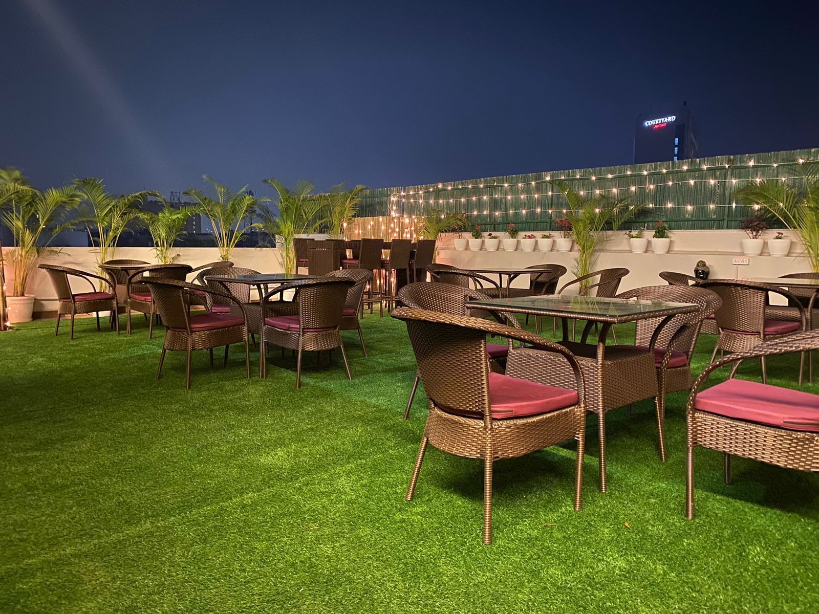 An outdoor seating area with wicker furniture and artificial grass, overlooking a building with a sign that reads "Courtyard."