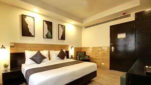 Camera d'albergo con un letto grande, una testiera in legno e tre quadri appesi alla parete.