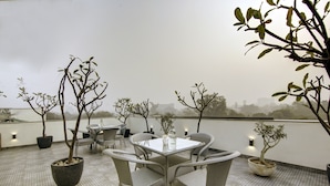 Una terrazza sul tetto con tavolo e sedie, piante in vaso e vista sullo skyline della città.