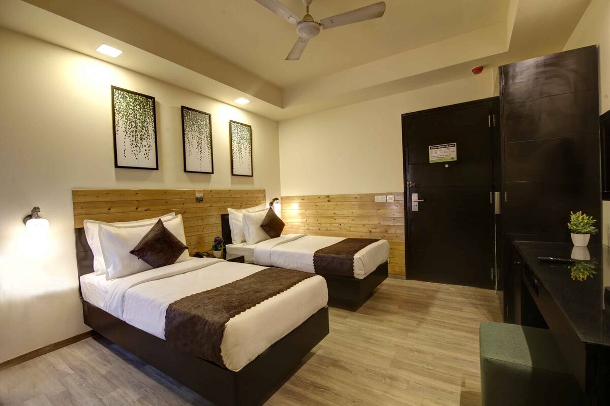 Una habitación de hotel con dos camas, cabecero de madera, ventilador de techo y una obra de arte en la pared.