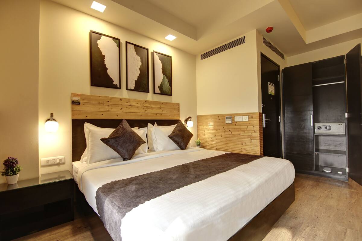 Una habitación de hotel moderna con una cama grande, cabecera de madera y tres obras de arte colgadas en la pared.