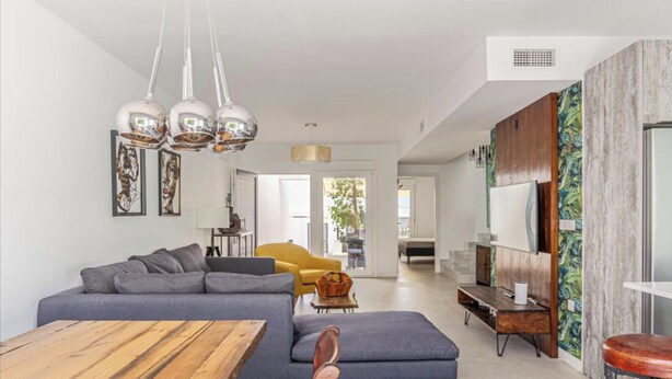 Una sala moderna con un sofá seccional gris, una mesa de comedor de madera y un sillón amarillo.