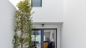 Un interior moderno con un vano visible que da a un comedor, una planta pequeña y un ventanal.