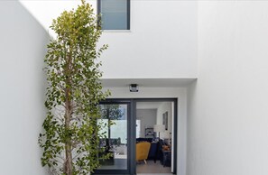 Contemporary room with a clean, white wall, dark-framed glass door, and a comfortable seating area.