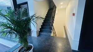 Una escalera con barandilla, una planta en maceta y un detector de incendios en la pared.