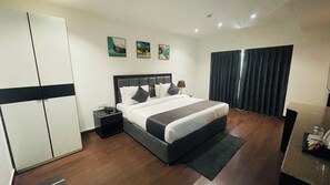 Una habitación de hotel moderna con una cama grande, un armario, una mesita de noche y un escritorio.