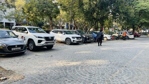 Un estacionamiento con varios coches y un hombre caminando.