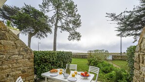 An outdoor dining area with a table set for two, surrounded by stone walls and greenery. - Les Terrasses de la Plage by Interhome (Carnac)