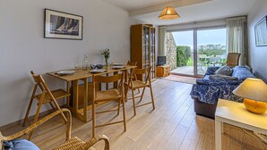 A dining area with a wooden table and chairs, a television, and a view of the outdoors. - Les Terrasses de la Plage by Interhome (Carnac)