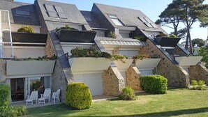 A modern multi-story building with a sloped roof, stone facade, and balconies with planters. - Les Terrasses de la Plage by Interhome (Carnac)