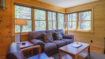 Una habitación acogedora con detalles de madera, un sofá, una mesa y una lámpara.