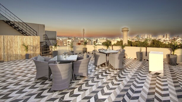 Una terraza en la azotea con mobiliario exterior, vistas a la ciudad y una torre de agua al fondo.