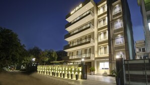 Un hotel moderno con un letrero que dice "SALT STAYZ" en la parte superior. Cuenta con varios pisos con balcones y una entrada bien iluminada.