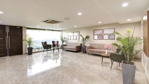 Un vestíbulo amplio con techo alto, un gran ventanal y una zona de estar con sofás y sillones.