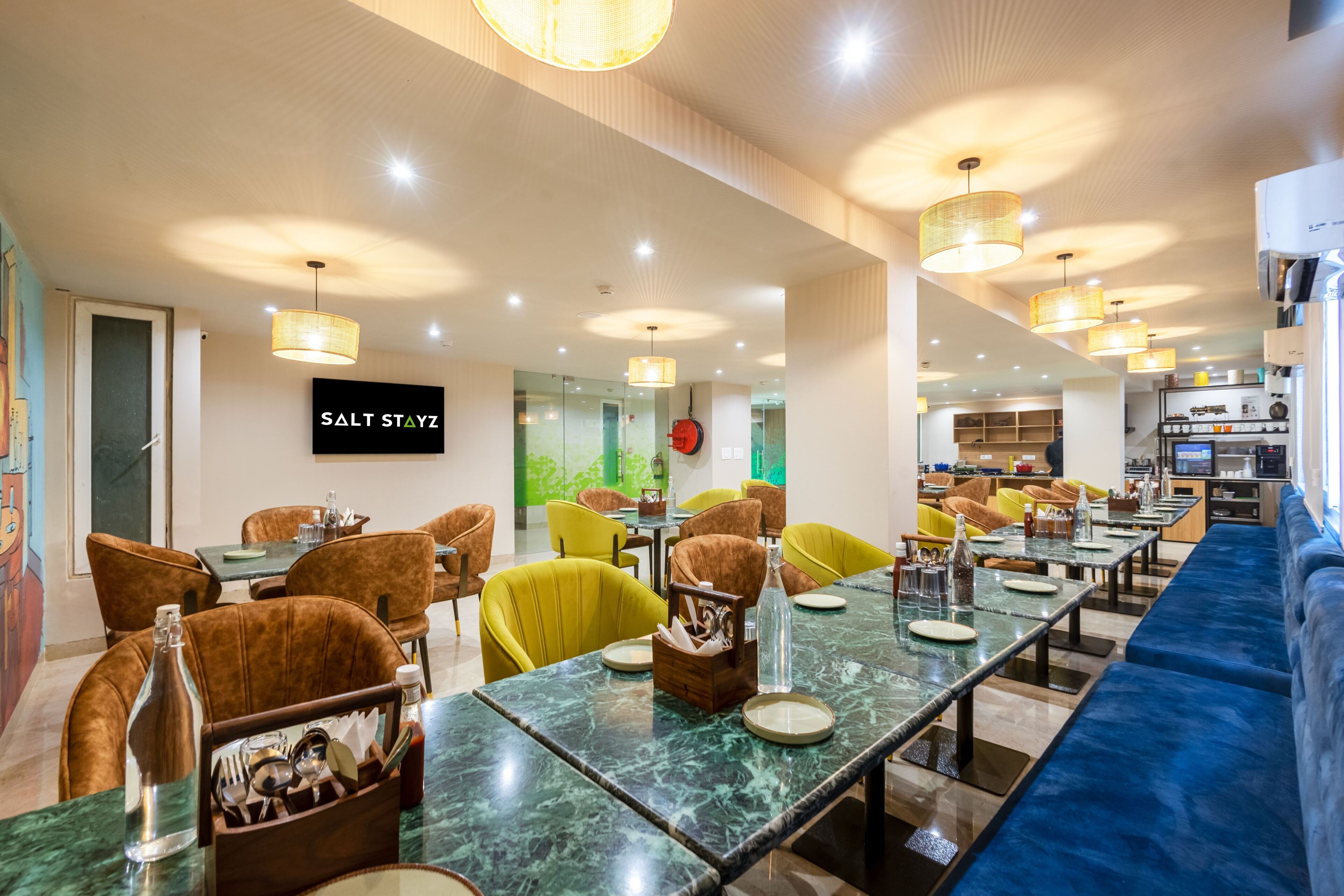 Um restaurante com mesas de mármore, cadeiras estofadas e iluminação pendente.