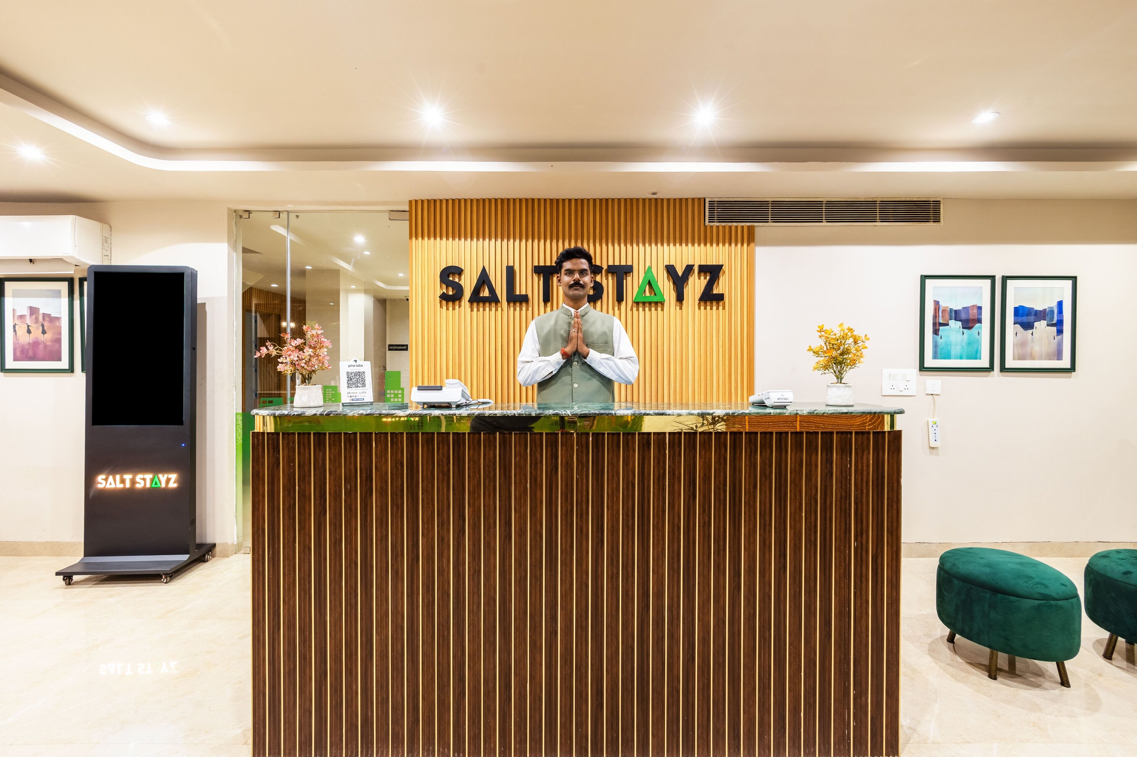 Un comptoir d’accueil avec un panneau décoratif en bois et l’inscription « SALT STAYZ » au-dessus.