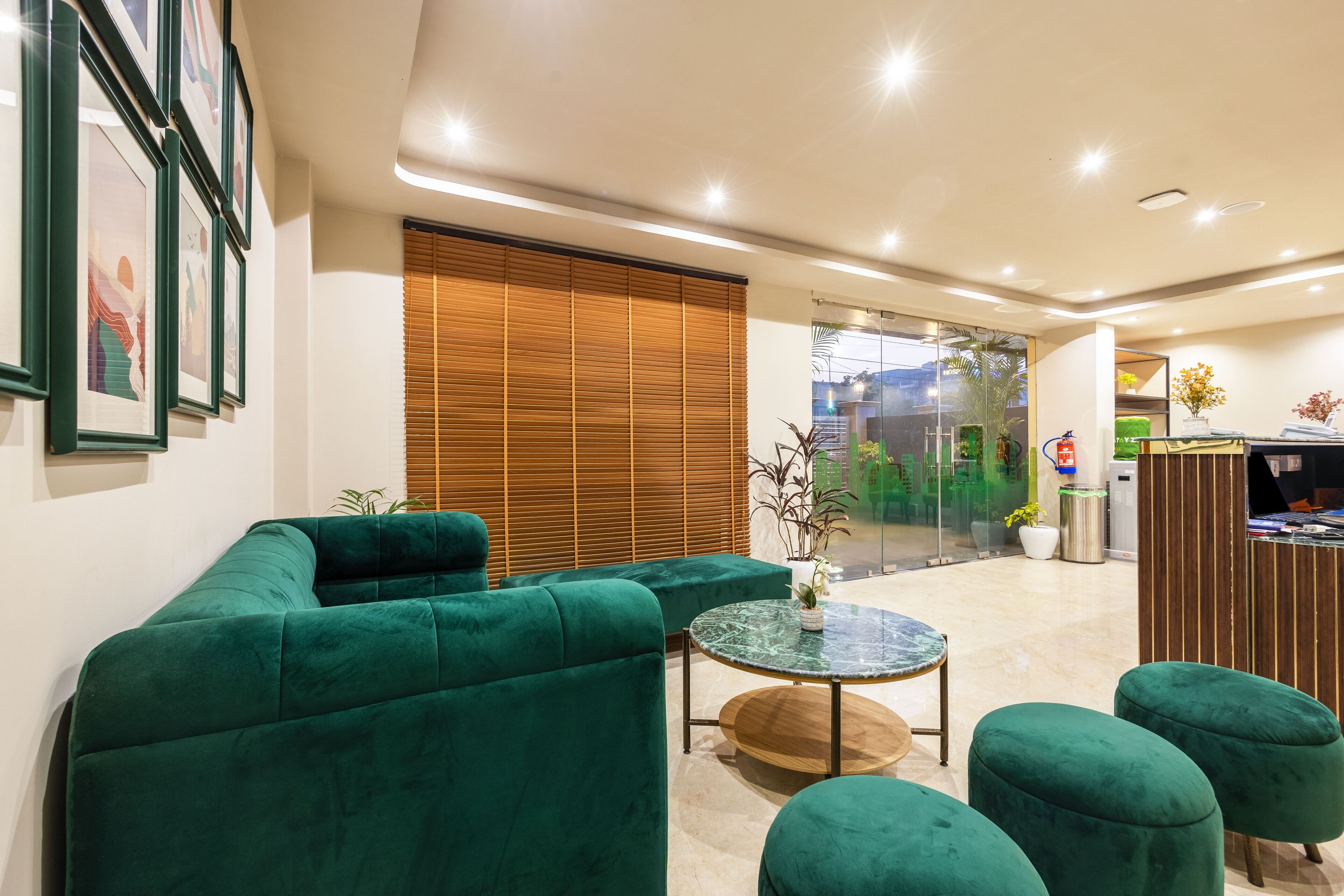 Een modern interieur met een groene zitbank, een ronde marmeren tafel en een houten receptiebalie.