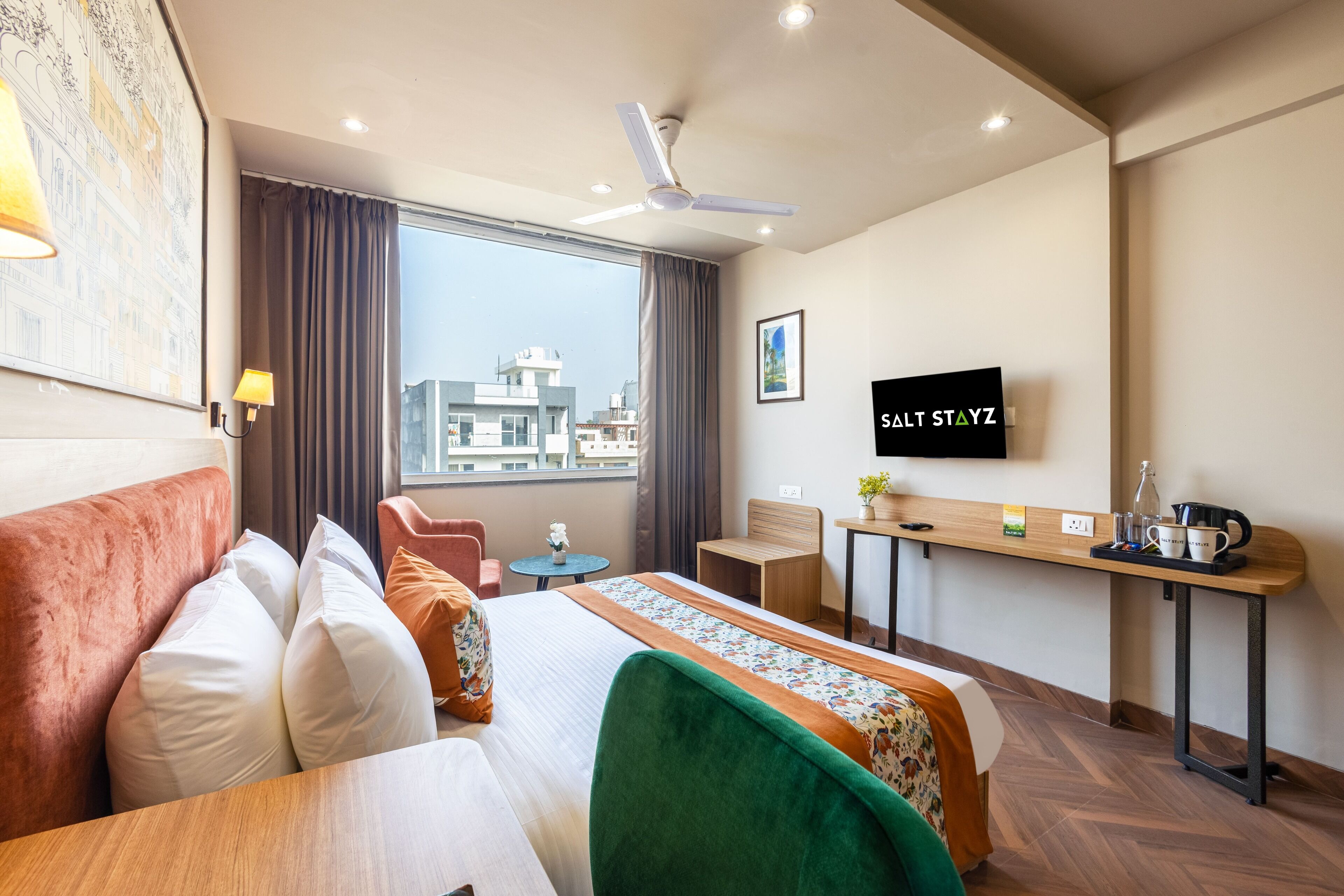Habitación de hotel con cama, escritorio, silla, televisor y ventana con vista a la ciudad.