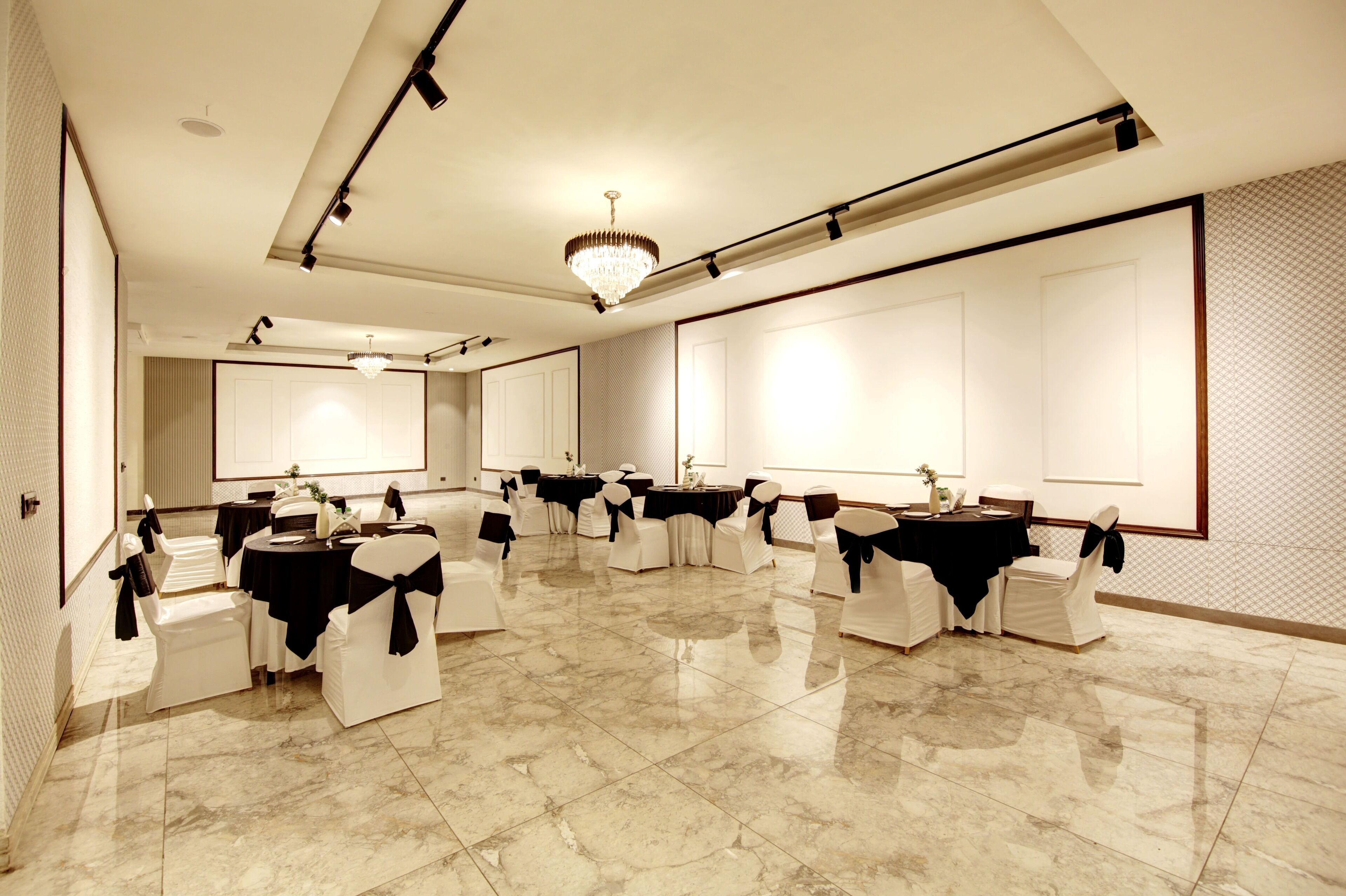Une salle de banquet spacieuse, dotée d’un sol en marbre poli, de plusieurs tables rondes et de chaises ornées de rubans noirs.