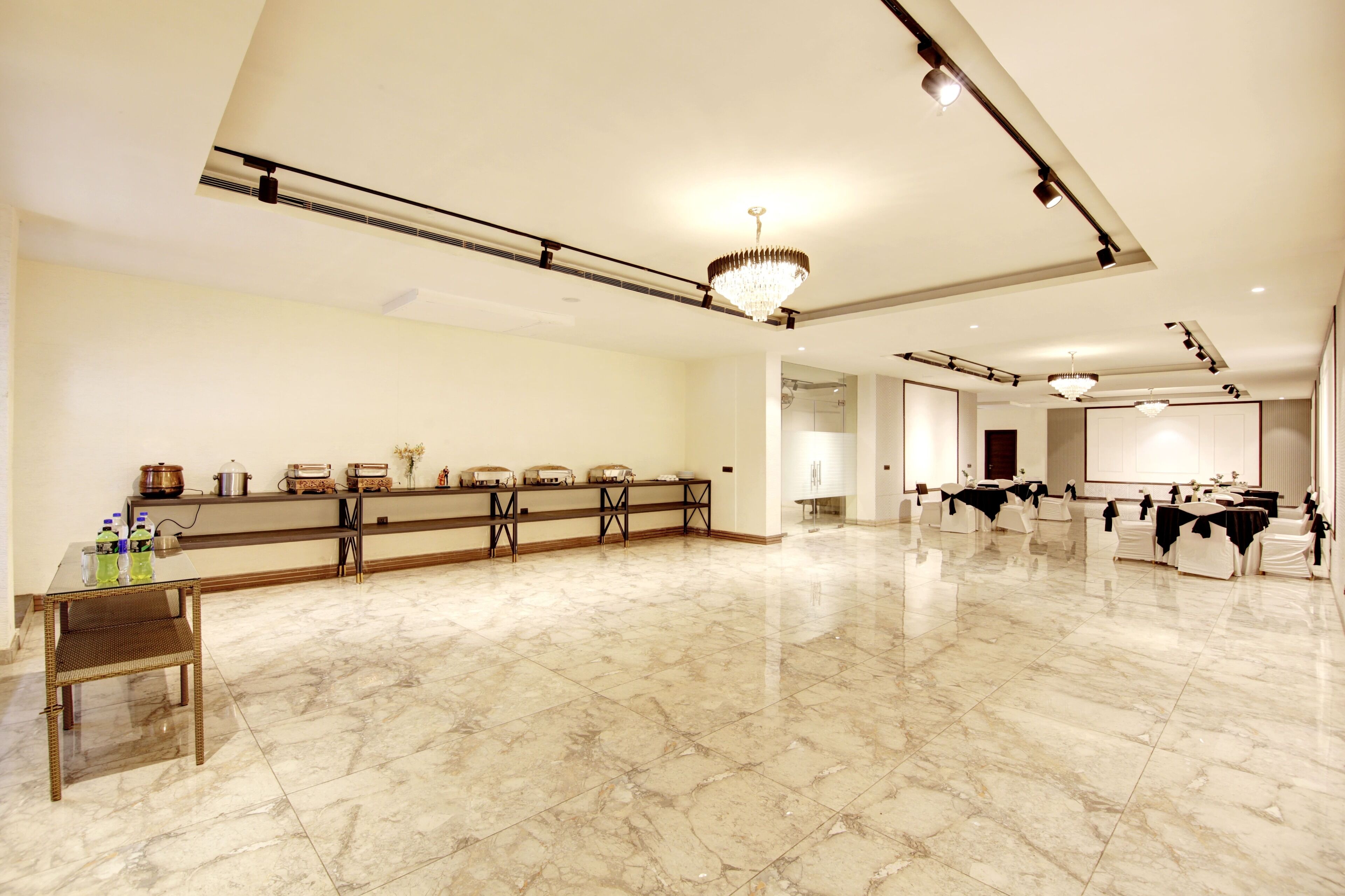 A spacious hotel lobby with a marble floor, a reception desk, and a seating area with chairs.