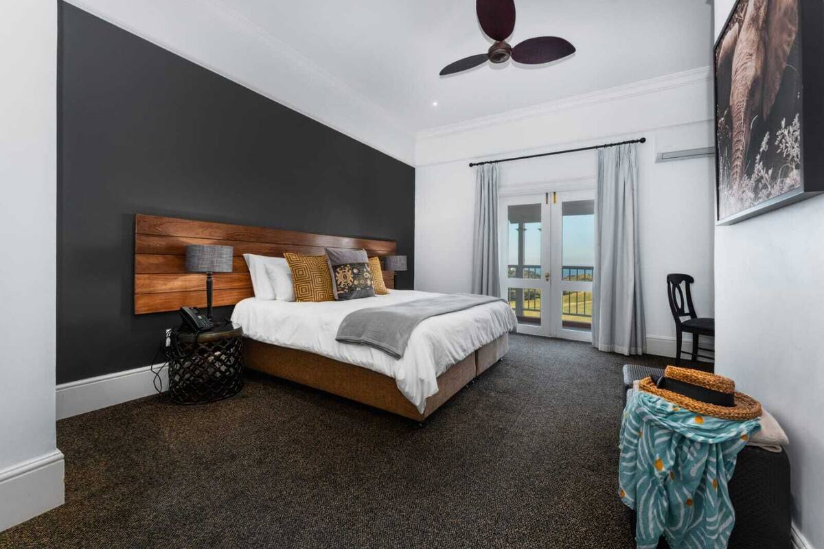 Een moderne slaapkamer met een groot bed, een plafondventilator, uitzicht op de omgeving en een balkon.