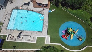 Vue aérienne d’un espace piscine avec un toboggan et des chaises longues.